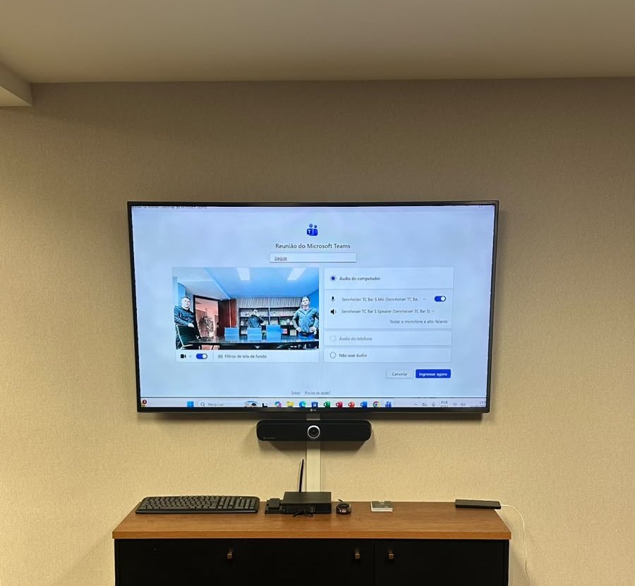 Barra de videoconferência e tela integradas em sala de reunião corporativa